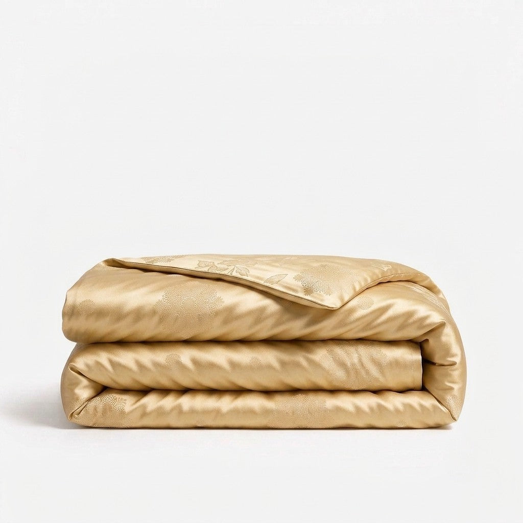 A folded gold silk duvet cover on a white background