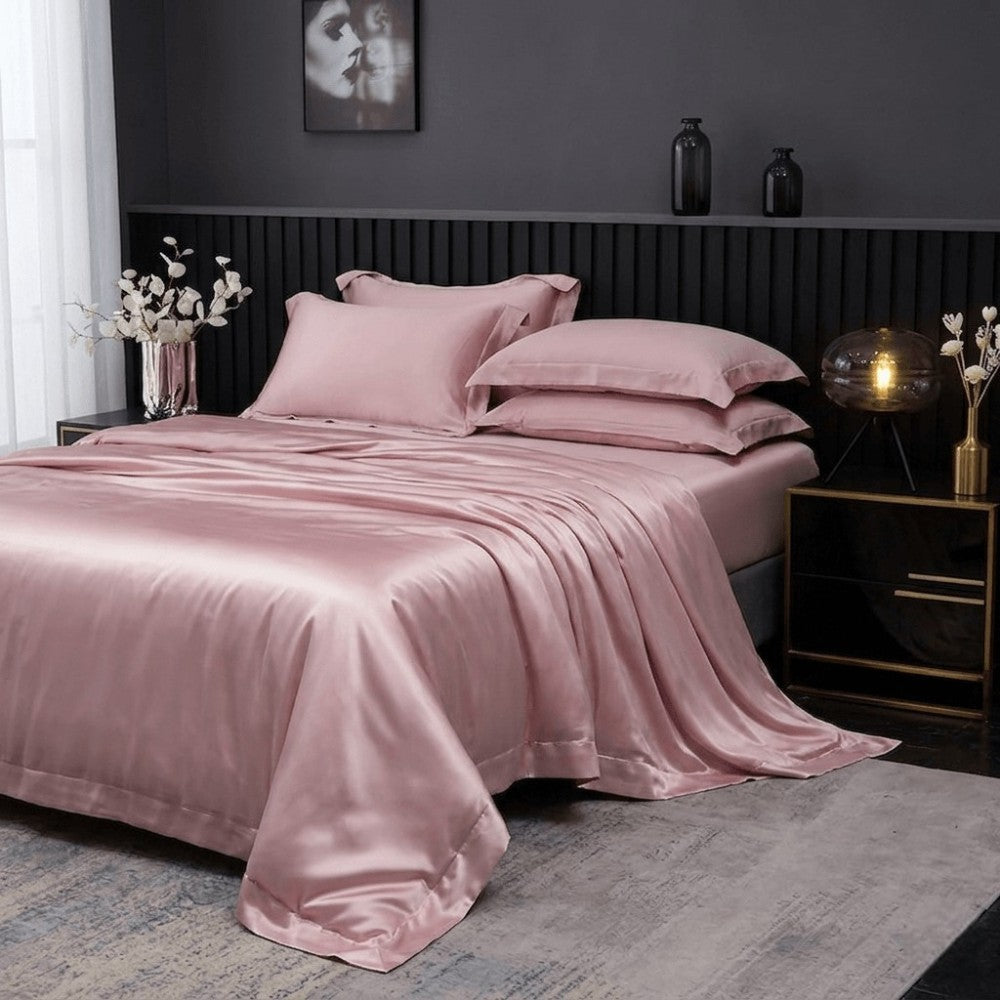Pink silk bedding set on a bed in a bedroom with dark walls and decorative elements.