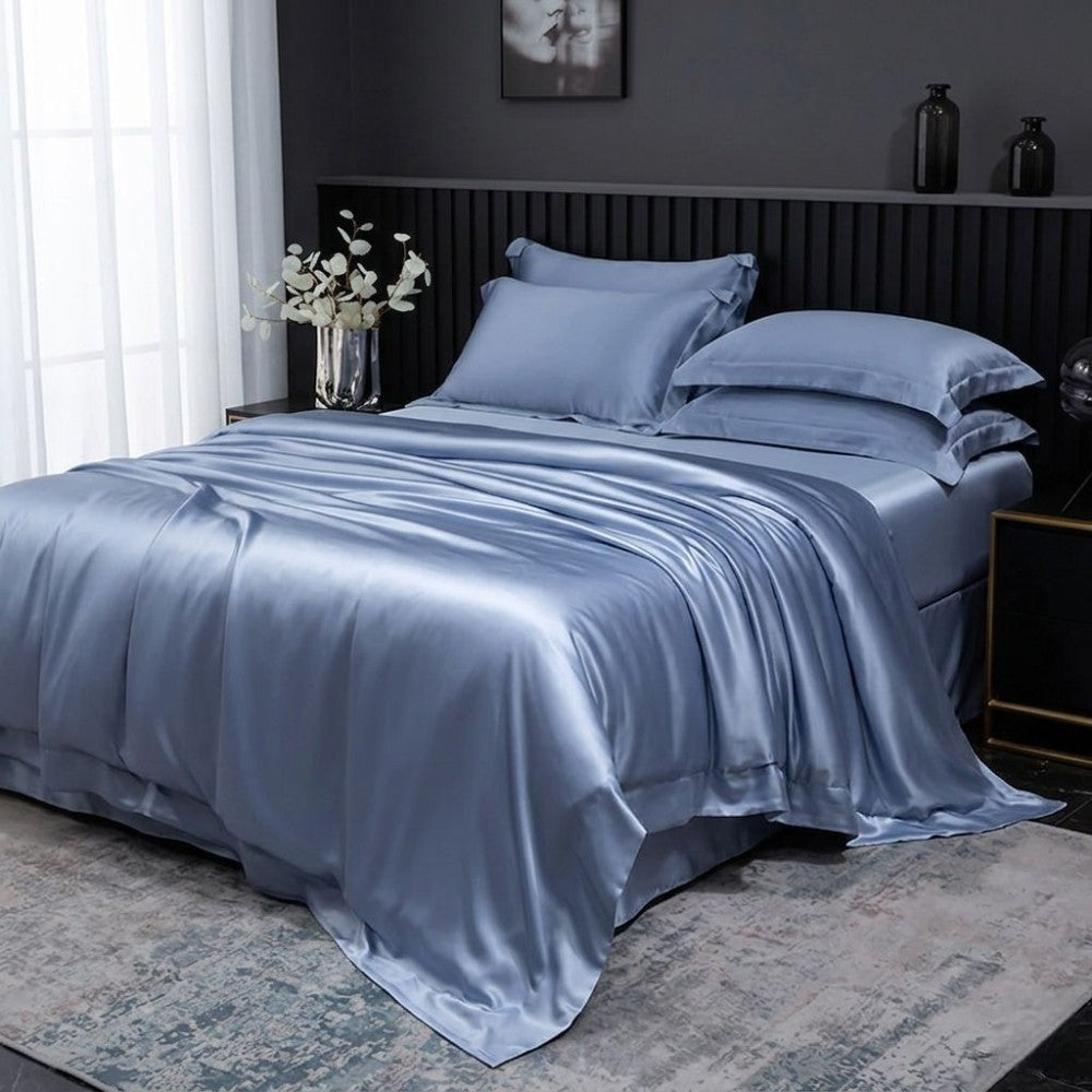 Blue silk bedding set on a bed in a bedroom setting.