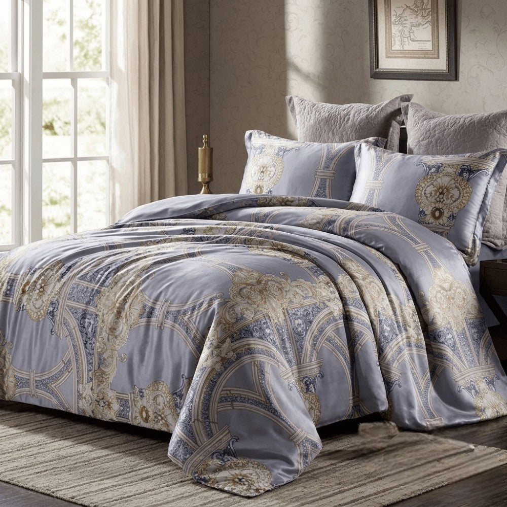 Patterned bedding set on a bed in a bedroom with a window and framed picture in the background.
