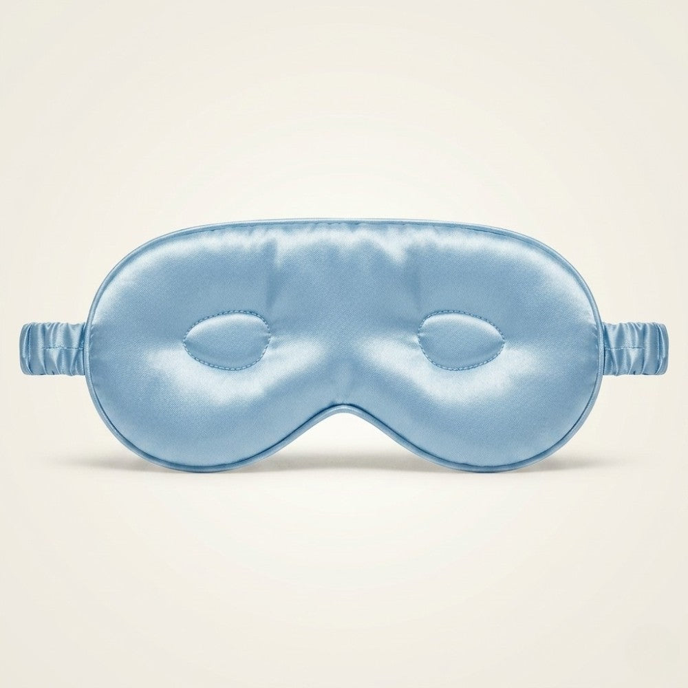 Blue silk sleep mask on a beige background
