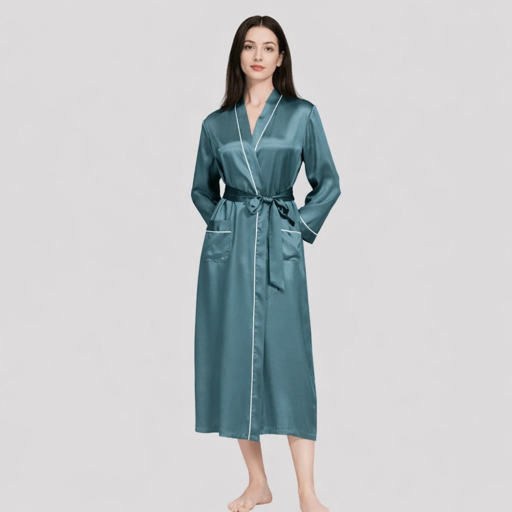 Woman wearing a teal satin robe on a light gray background