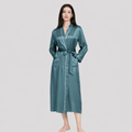 Woman wearing a teal silk robe on a light gray background