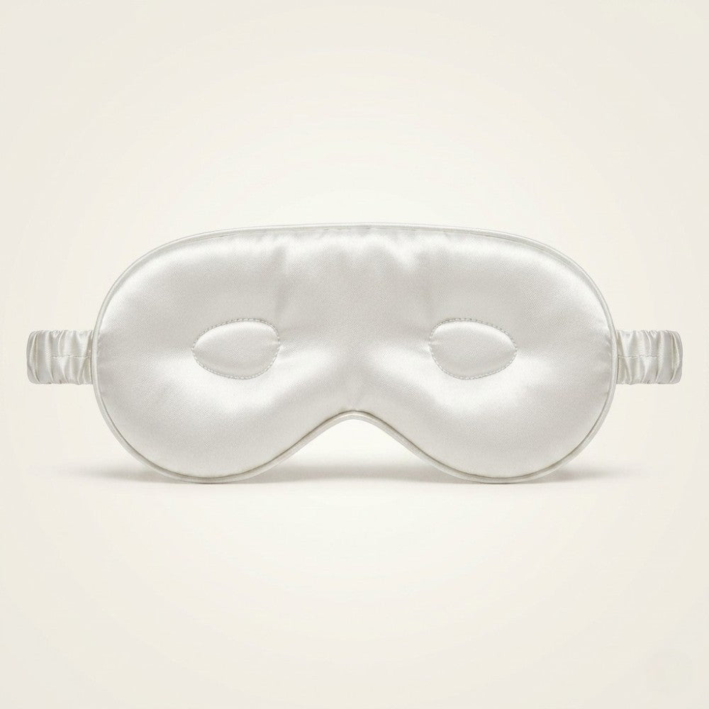 Silky white sleep mask on a light beige background